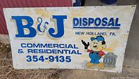 Front of metal sign showing B&J Disposal graphics and text