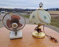 Lamp and fan side by side on table