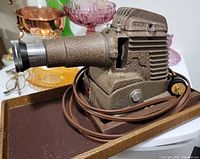 Projector on its case showing body, lens, cord