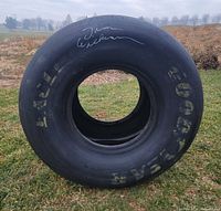 Full view of racing slick tire standing upright on grass