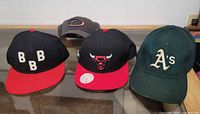Front view of all four hats displaying logos and colors