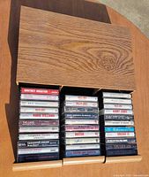 Open box with three drawers extended, showing 32 cassette tapes