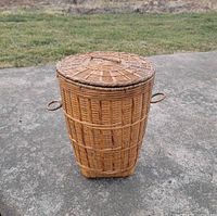 Full view of cylindrical wicker basket with lid and side handles
