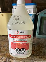 Front view of sealed 4 L UBA hydrochloric acid jug showing label and safety symbols