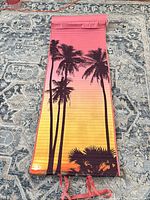 Full view of rolled-flat mat showing palm sunset print and tie straps