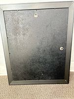 Back of black picture frame showing hanging hardware