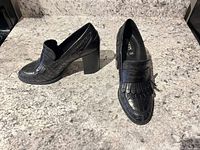 Full pair of Geox black croc-embossed loafers on granite surface