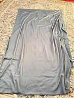 Full view of folded blue velour fabric laid out on rug