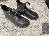 Full view of left and right boots showing uppers and toe wear