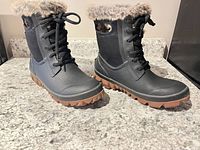 Side view of both boots showing uppers, laces, faux fur trim