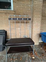 Front view of metal coat rack bench showing hooks, seat, shelf