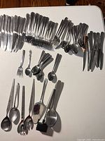 Overview of assorted stainless steel knives, forks, spoons and serving pieces on table