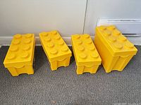 Four LEGO brick-shaped storage boxes with lids closed
