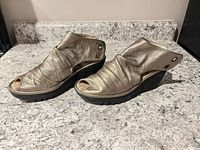 Side view of pair showing metallic leather, wedge heel, open toe