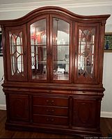 Front view of full wooden china cabinet showing glass doors, drawers, cupboards