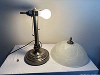 Full view of lamp base lit and separate frosted dome shade
