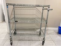 Front view of three-tier metal wire cart on casters