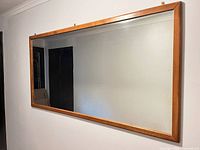 Front view of rectangular wood-framed mirror mounted on wall