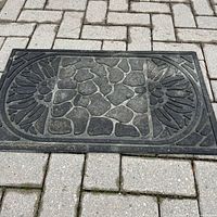 Top view of entire black rubber doormat showing raised patterns and border