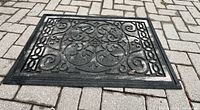 Top view showing full rectangular rubber doormat with raised scroll pattern