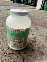 Front view of H&C SharkGrip additive jar showing label and handwritten tape