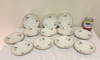 Front view of 12 matching saucers showing pattern and gold rim