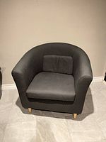 Front view of first dark grey tub chair showing overall style and condition