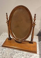Front view of oval tilting mirror on wood base