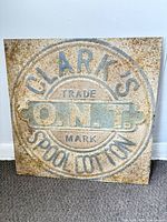 Front of square Clark's O.N.T. metal sign showing full embossed design and color