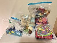 Multiple resealable bags containing yarn, loom kit and elastic bands on table