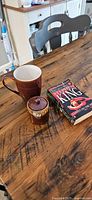 Mug, lidded jar and stack of four paperbacks on table