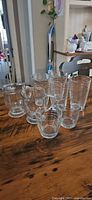 Eight clear ribbed glasses: four tall tumblers behind, three smaller glasses front and one mug
