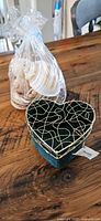 Heart-shaped velvet jewelry box and bag of seashells on wood table