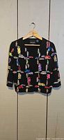 Full front view of black cardigan jacket with multicolor vehicle embroidery