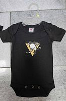 Full view of one black baby onesie with Penguins logo, hanger visible