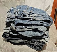 Stack of six folded jeans on white background