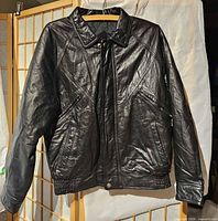 Front view of black leather jacket hanging, showing overall style