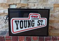 Front view of rectangular light box sign with power cord, displaying “London Young St” graphic