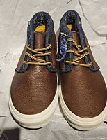 Top view of both boots showing leather uppers, denim collar, laces and tag