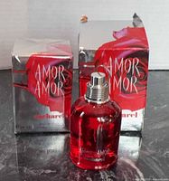 Two boxes and one red glass bottle of Amor Amor Cacharel