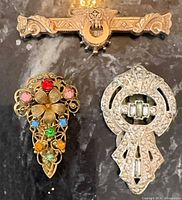All three jewellery pieces laid out: gold bar brooch, multicolour rhinestone fur clip, silver rhinestone fur clip