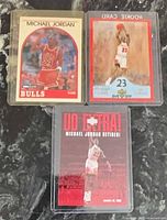 All three Michael Jordan cards in protective sleeves displayed on countertop