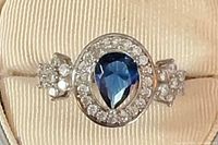 Front view of sterling silver ring showing pear blue stone and CZ halo
