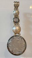 Front view of pendant showing pearls, smoky quartz, carved glass flower disc and bail