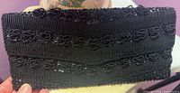 Front view of entire black beaded clutch showing bead pattern and flap