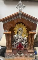 Frontal view of wood icon altar with silver figures and red lamp