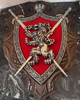 Full view of wood shield plaque with red velvet, metal lion and swords