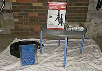 Lot overview showing jack stand box, sealed filter, oil drain pan, sponge on table