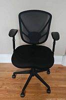 Front view of chair showing mesh back, fabric seat, adjustable arms, caster base