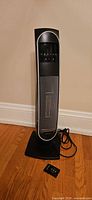 Front view of tower heater with remote and power cord visible